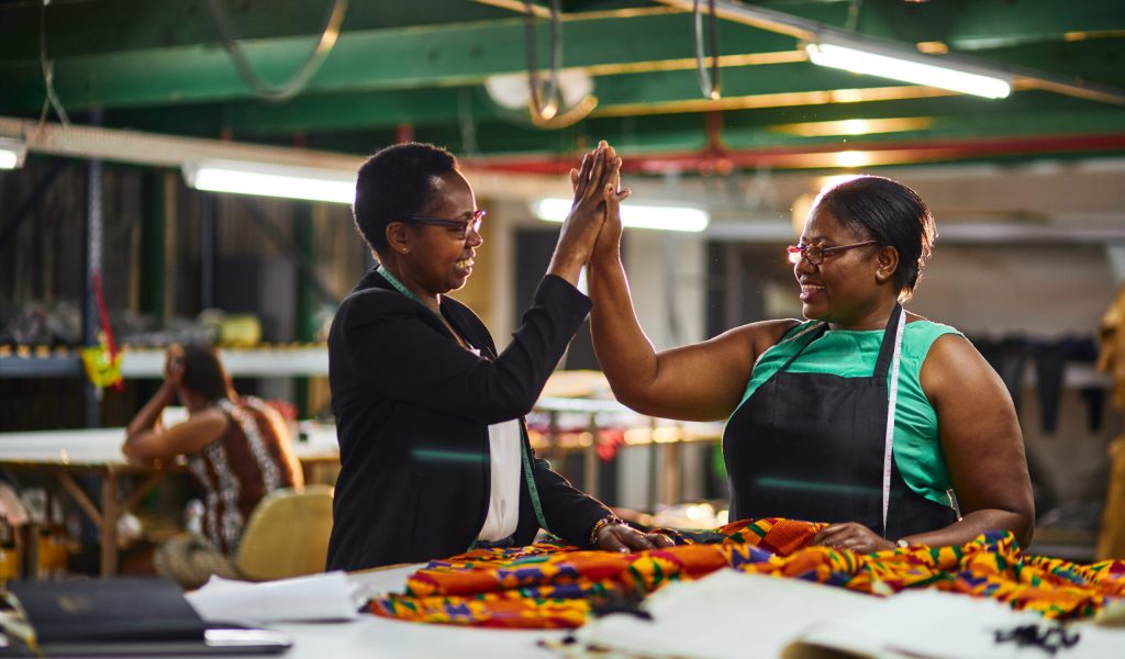 african business woman of textile factory wearing a black jacket with a white blouse giving employee high 5